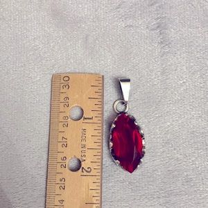 This is a silver pendant with a red stone or glass.